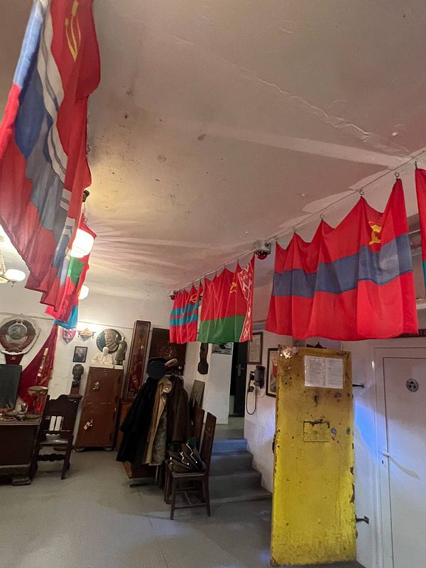 Bust of a prominent figure in front of a vivid mural featuring a soldier and a dog at the underground KGB museum.