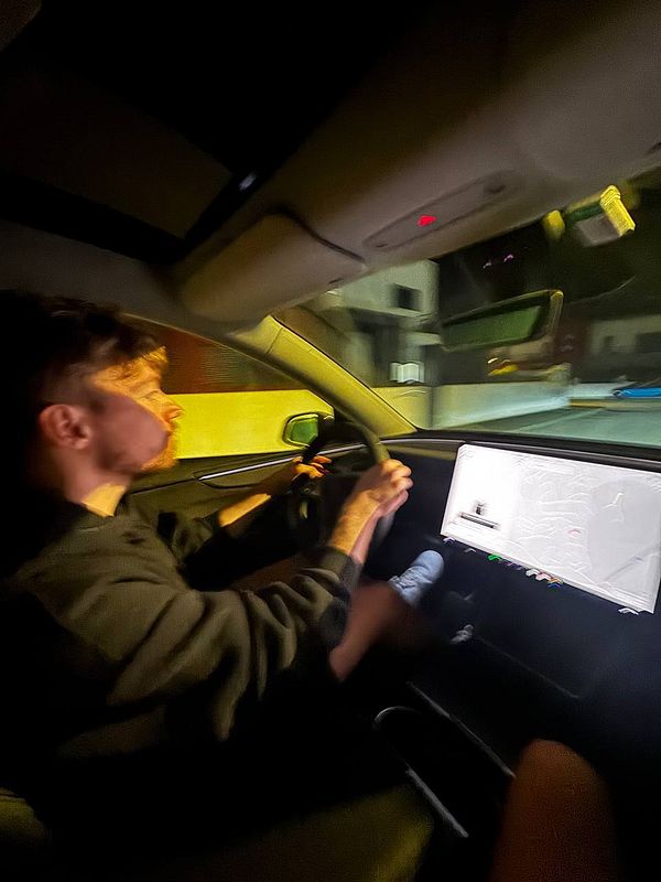 A person is practicing parking a car at night, focusing on the vehicle's dashboard display.