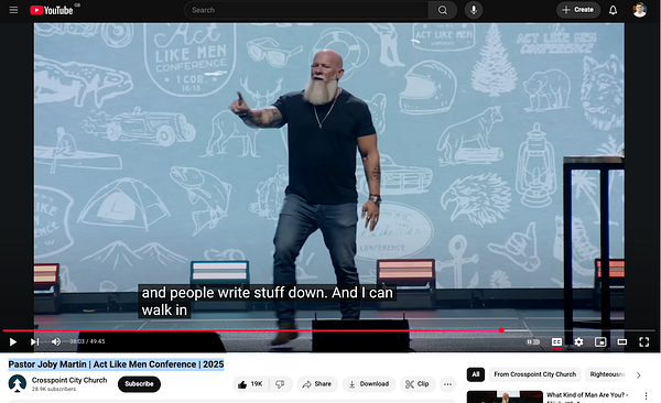 A speaker presents at the Act Like Men Conference, engaging the audience with a dynamic expression.