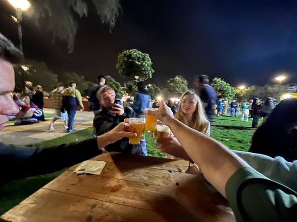 A group of friends is celebrating with drinks at a festival at night.