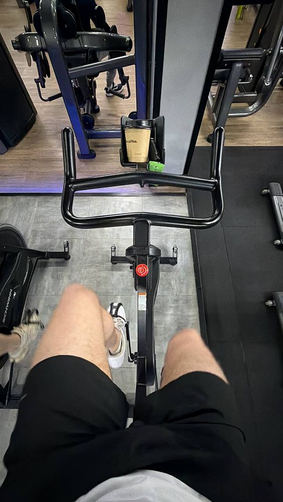 A woman in athletic wear poses on a rooftop gym with the city skyline in the background.