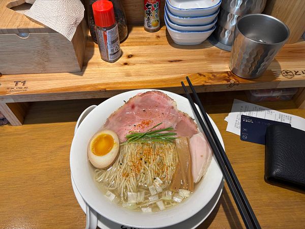 A bowl of Japanese ramen with various toppings is presented on a wooden table.