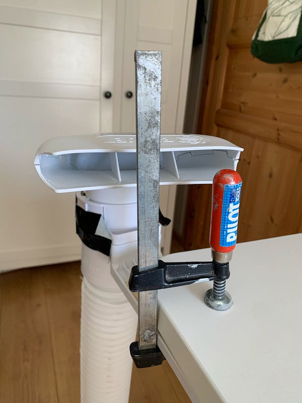 A DIY cooling solution using a clamp and a plastic duct.