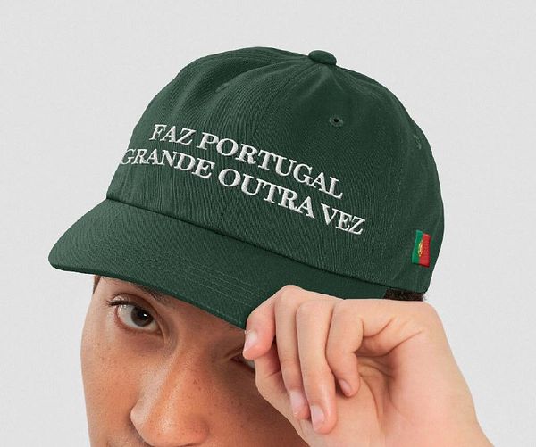 A person is wearing a green cap with a Portuguese phrase embroidered on it.