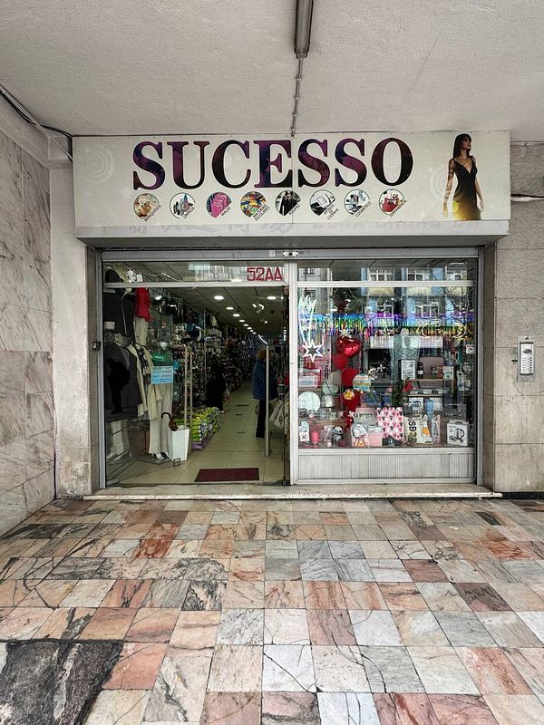 A storefront of a shop named 'SUCESSO' with various items displayed inside.