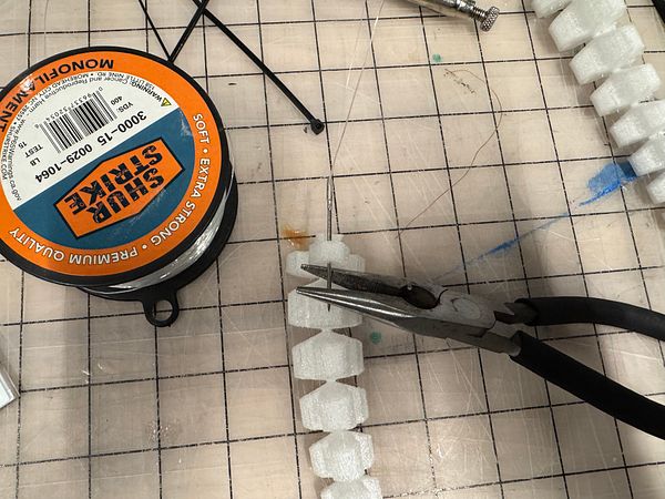 The image features crafting materials and tools for threading tentacles.