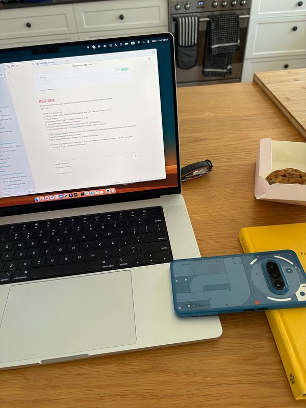 A workspace featuring a laptop, a smartphone, a book, and a box of cookies.