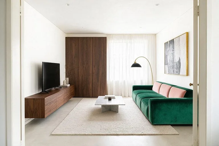A Minimalist living room in the Emerald Velvet palette: white, emerald green, blush, walnut, and brass