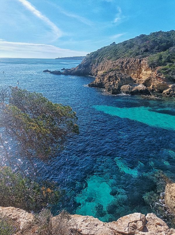 A scenic coastal view featuring clear blue waters and rocky cliffs.