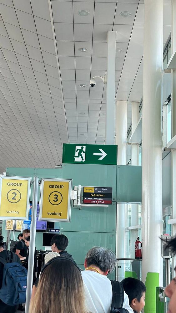 The image captures a busy airport boarding area with a focus on a flight to Paris.