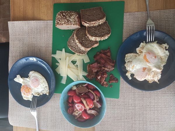 A Croatian-style lunch featuring bacon, eggs, cheese, and a salad.