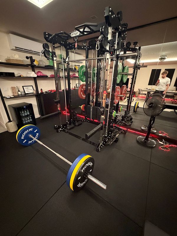 Interior view of a well-equipped gym with various fitness equipment and wood flooring.
