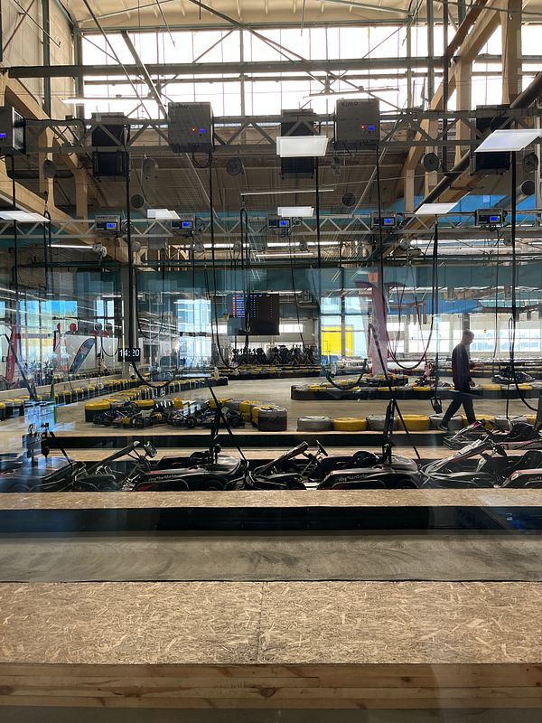 An indoor go-kart track with karts lined up and a viewing area.