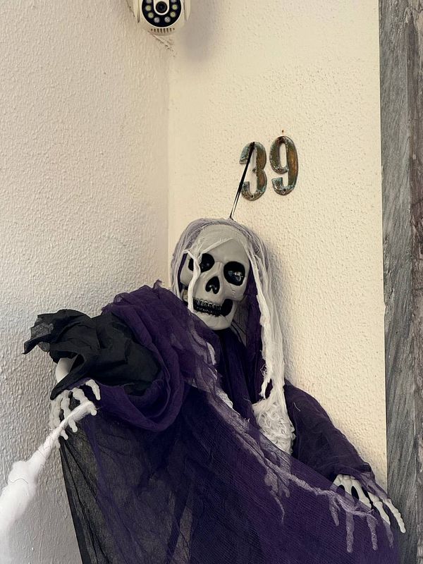 A skeleton dressed in a purple and black cloak is positioned near a wall with the number 39.