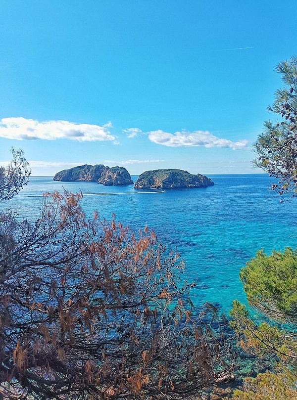 A scenic view of two islands surrounded by clear blue water under a bright sky.