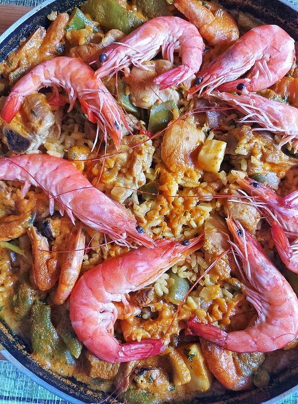 A vibrant paella dish featuring large shrimp and colorful vegetables.