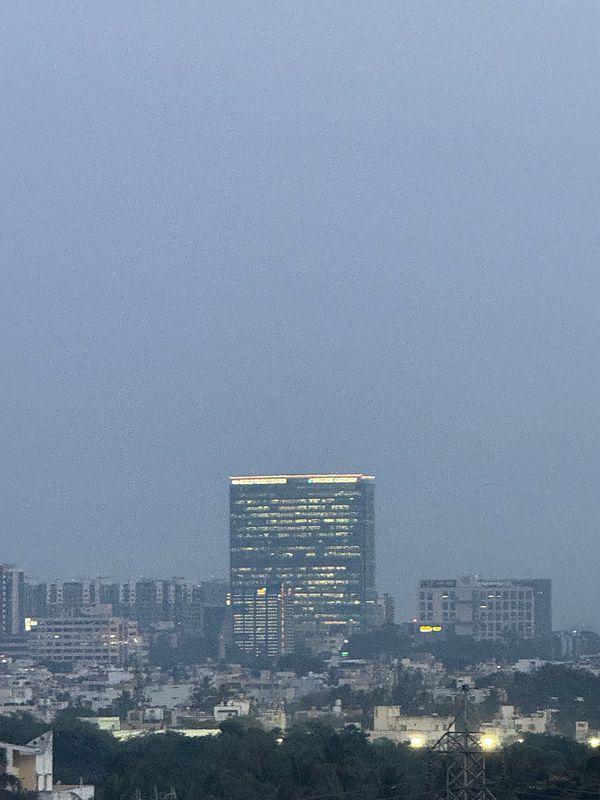 A city skyline is visible under a cloudy sky during sunset.