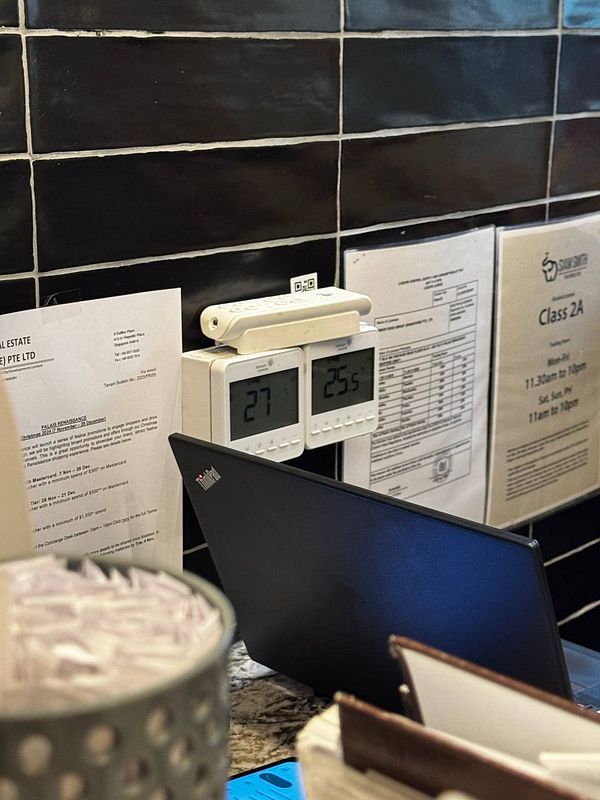 The image features a workspace with temperature displays and various documents.