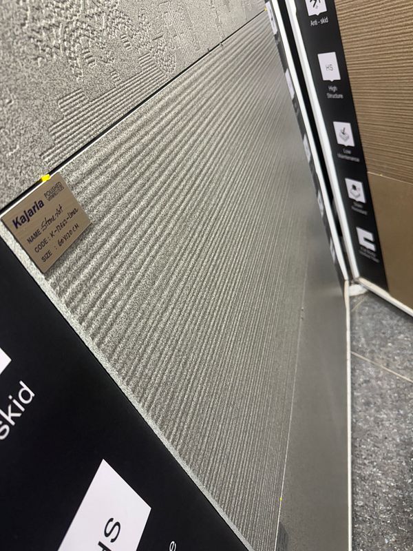 The image features a display of textured wall tiles in a showroom setting.