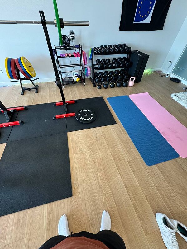 A home gym setup featuring various workout equipment and mats.