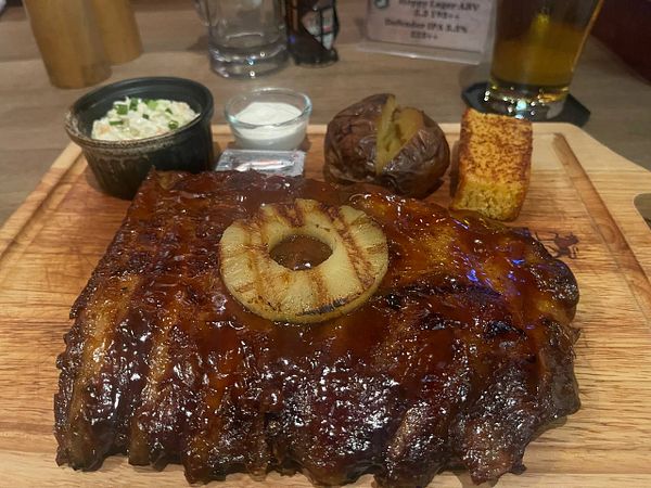A delicious American BBQ meal featuring ribs, sides, and a drink.