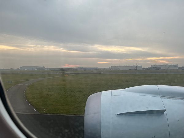 The image captures the view from an airplane window during landing at Amsterdam Airport Schiphol (AMS).
