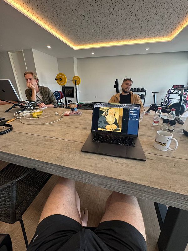 A coworking space featuring two individuals engaged in work, with a laptop displaying an illustration.
