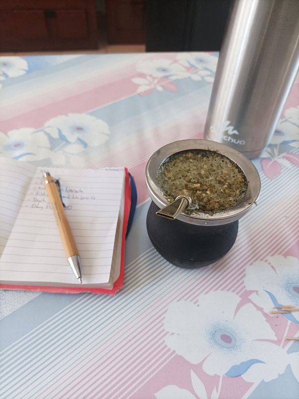 A workspace featuring a traditional mate setup alongside a notebook and a pen.