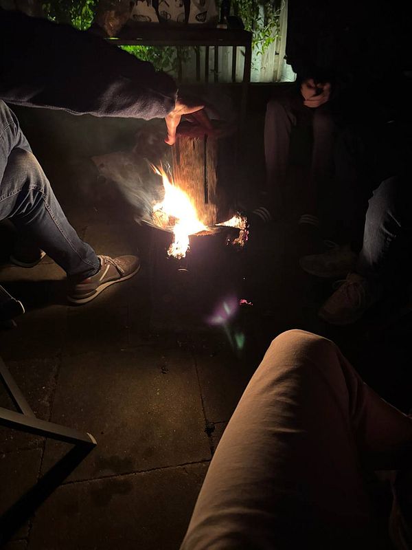 A cozy campfire gathering with friends in a dimly lit setting.