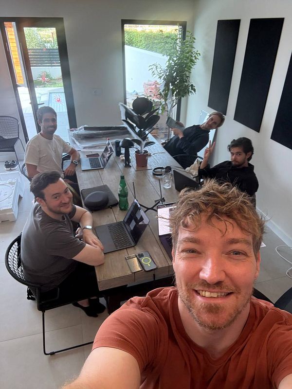 A group of five people is gathered around a table in a bright coworking space.