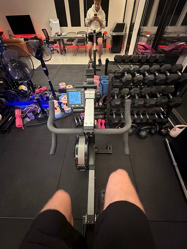 A woman in a gym setting, performing a cable tricep pushdown exercise with a personal trainer assisting.