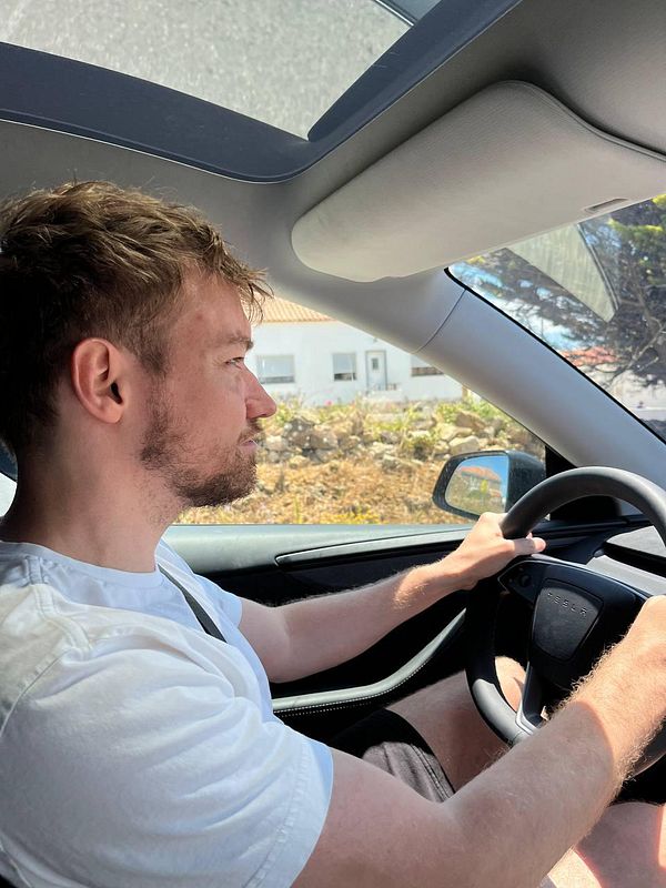 A person is driving a car on a sunny day, with a focus on the road ahead.