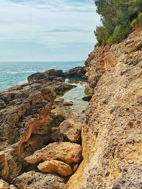 A rocky coastal landscape with clear water pools and a view of the ocean.