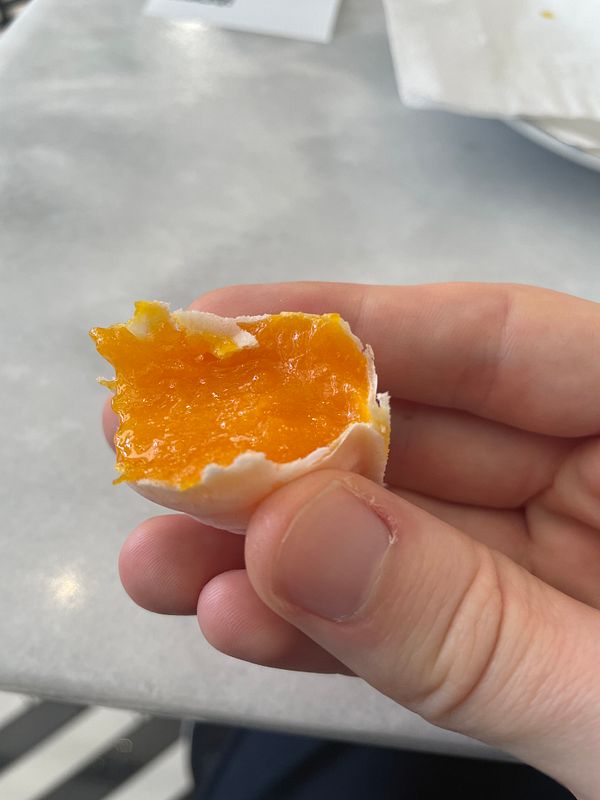 A hand holds a partially eaten Ovo Mole, revealing its bright orange filling.