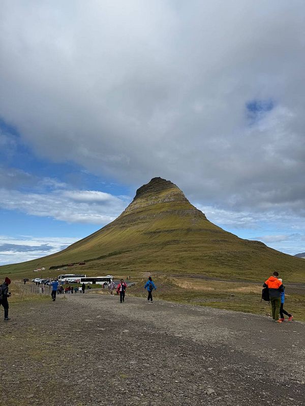 A scenic view of Kirkjufell mountain with visitors walking along a gravel path.