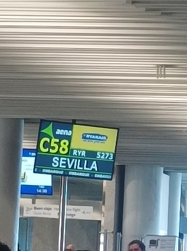 An airport departure board displaying a flight to Sevilla.