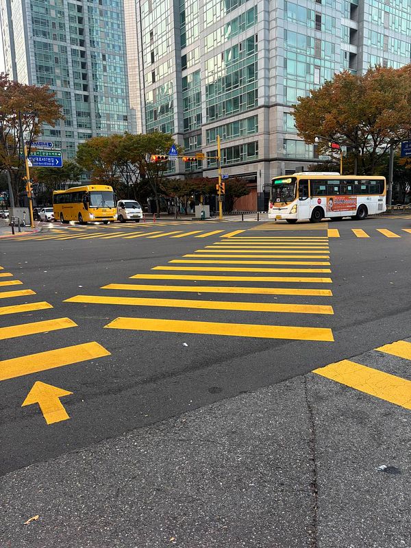 A busy urban intersection featuring two buses and modern high-rise buildings.