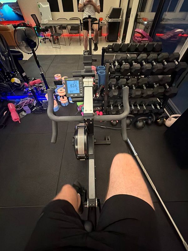 A photograph of an outdoor gym area with two people exercising on different fitness machines.