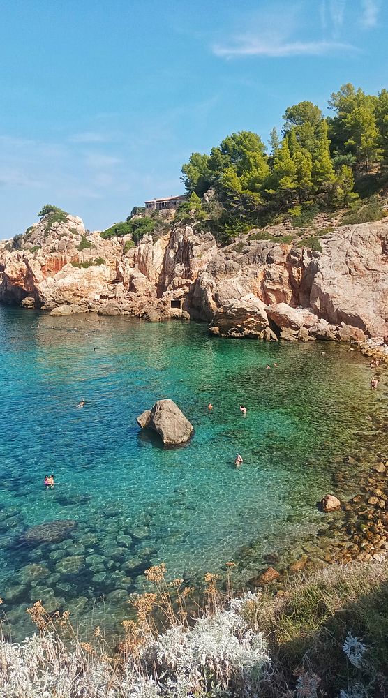 A picturesque coastal scene featuring clear turquoise waters and rocky cliffs.