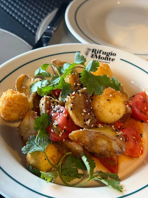 A vibrant dish featuring crispy potatoes, tomatoes, and garnishes served at a restaurant.