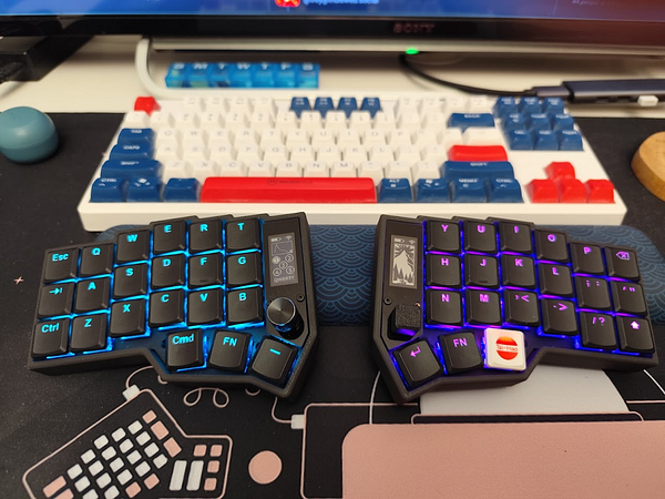 The image features two compact mechanical keyboards positioned on a desk with a colorful background.