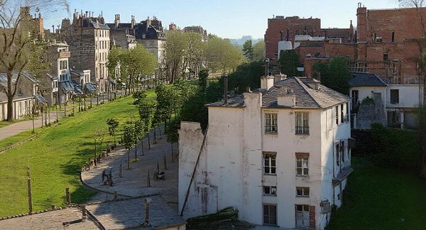 A panoramic view of a historic Parisian street lined with trees and old buildings.