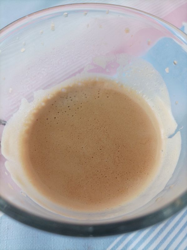 A close-up view of a glass containing a creamy espresso.