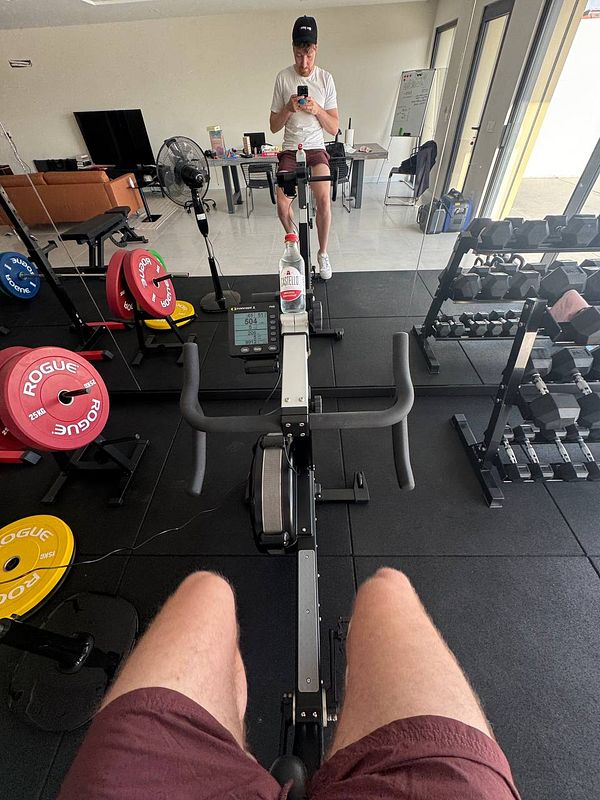 A person is seated on a rowing machine in a home gym setting.