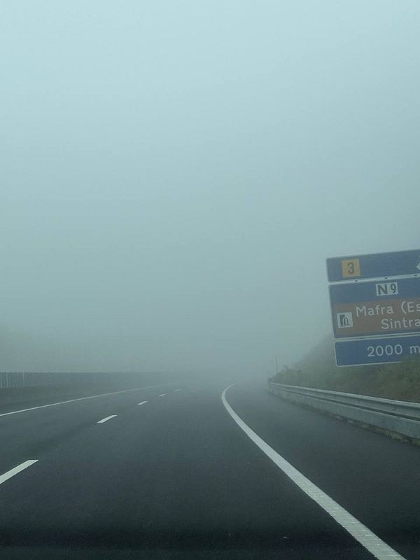 A foggy highway scene with a directional sign visible.