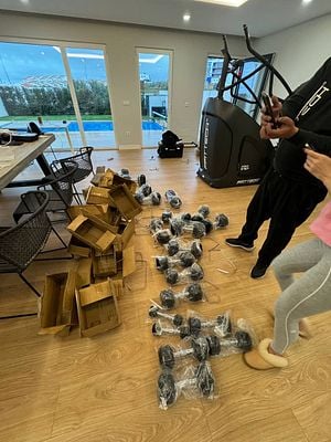 A home gym setup in progress with unpacked equipment and a view of a pool outside.