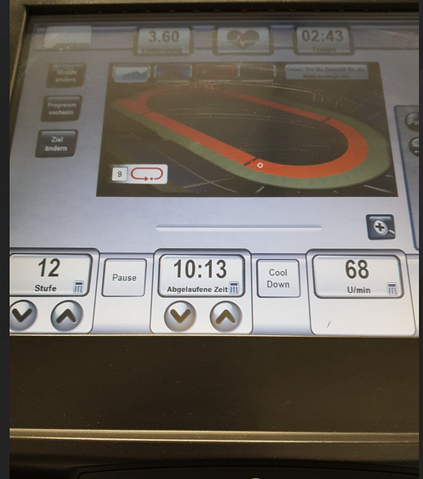 The image displays the control panel of a treadmill with various workout metrics and a visual track layout.
