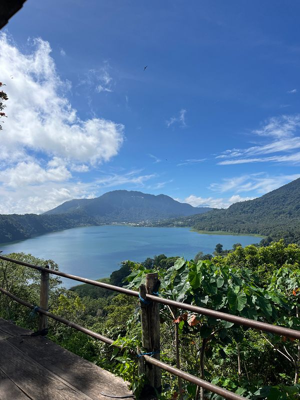 A scenic view of a lake surrounded by mountains and lush greenery under a clear blue sky.