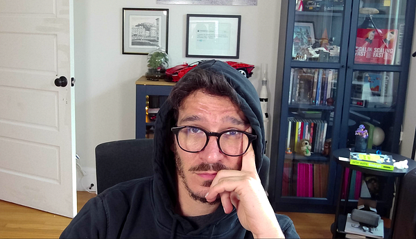 Interior of a store with multiple glass display closets holding various items and a wooden divider with a dartboard above it.