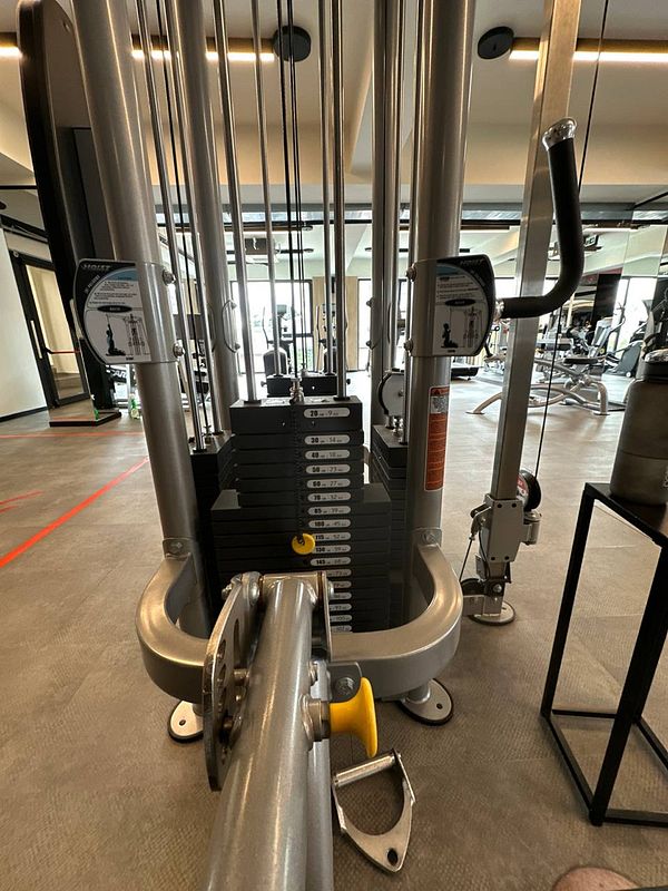 A gym weight machine with stacked weights and exercise handles in a modern fitness facility.